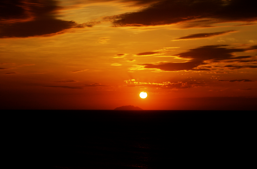 Atardecer desde la costa oeste de Puerto Rico. La isla visible en el horizonte pertenece al archipiélago borincano y se llama Desecheo.